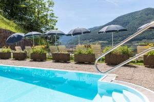 塞格扎诺阿里皮拉米德酒店的游泳池配有遮阳伞和椅子,背景为山脉