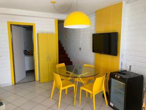 马拉戈日Paraíso Pé na Areia em Maragogi的一间设有玻璃桌和黄色椅子的用餐室