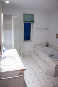 滨海圣吕斯Maison rose du bord de mer à 5 min de st Luce的白色的浴室设有浴缸和水槽。