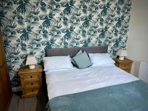 MonkwearmouthMilburn Cottage 2- Luxury Accommodation的一间卧室配有一张带绿色和白色壁纸的床