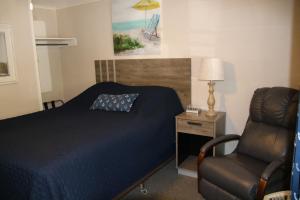 克莱顿West Winds Motel & Cottages的一间卧室配有一张床、一把椅子和一盏灯