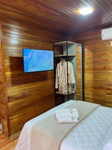 邦雅尔丁-达塞拉Recanto da Maju的一间卧室配有一张床,墙上配有电视