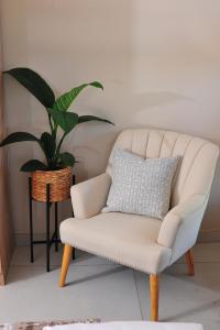 哈博罗内Square Connexions Guest House的客厅的白色椅子,植物