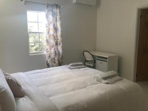 Newcastle VillageCompassionate Touch Spa的一张白色的床,位于带椅子和窗户的房间