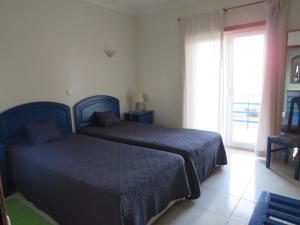 西尔维拉Hotel Apartamento Praia Azul的一间卧室设有两张床和大窗户