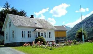 Uskedalen顿豪格耶斯特加德住宿加早餐旅馆的坐落在郁郁葱葱的绿色田野顶部的白色房子