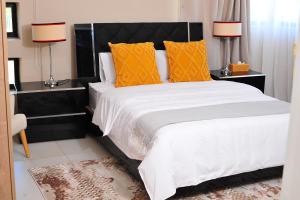 哈博罗内Square Connexions Guest House的一间卧室配有一张带橙色枕头的大床
