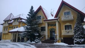 罗兹尤卡酒店的一座大黄色的建筑,地面上积雪