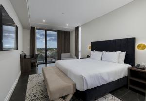 悉尼Crowne Plaza Sydney Burwood, an IHG Hotel的一间卧室设有一张大床和一个大窗户