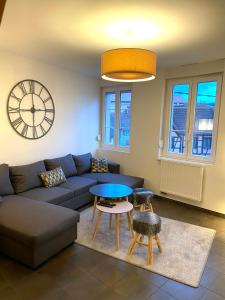 万泽内姆Duplex moderne à 10 minutes de Colmar的带沙发、桌子和时钟的客厅