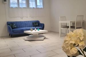 OsnyTulsa Home - Superbe appartement de deux chambres - avec terrasse privée的客厅配有蓝色的沙发和桌子