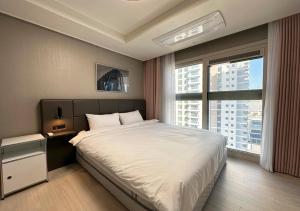 釜山Y Collection by UH FLAT Osiria的一间卧室设有一张大床和一个大窗户