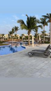 塞拉莱Hawana salalah Apartment Acacia的一座棕榈树游泳池毗邻度假酒店