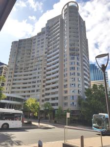 悉尼Chatswood Hotel Apartment的一座大型建筑,前面有一辆公共汽车
