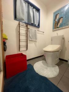 大阪spaceMU的浴室设有白色卫生间和红色凳子。