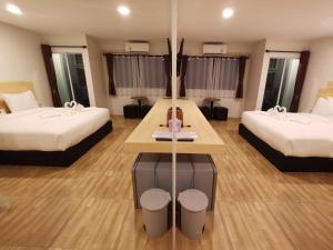 华富里The charlotte smart hotel lopburi的酒店客房设有两张床和一张桌子。
