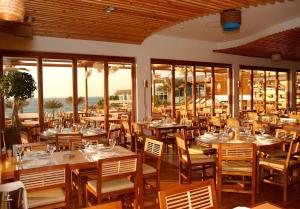 迪拜迪拜海滩Spa度假酒店的餐厅设有木桌、椅子和窗户。
