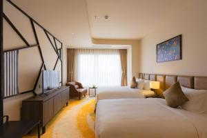 顺化La Vela Hue Hotel的酒店客房设有两张床和电视。