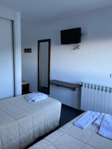 塞哥维亚Hostal La Pinilla的配有两张床铺的客房,墙上配有电视