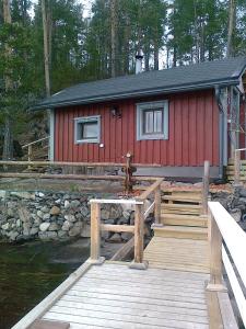 萨翁林纳Rantakallio Savonlinna, Tervetuloa meille!的红色小屋,设有毗邻水面的木头码头