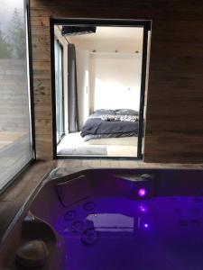 布吕兹Loft privatisé avec spa XXL et piscine chauffée的卧室前设有带紫色浴缸的浴室