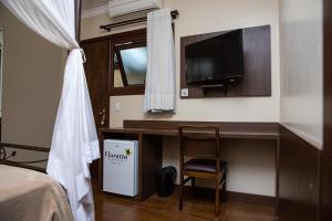格拉玛多Hotel Premium的一间卧室配有书桌、电视和椅子