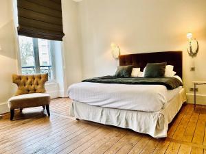 里摩日La Villa Beaupeyrat - Apparthôtels de charme dans bâtisse de caractère的一间卧室配有一张大床和一把椅子