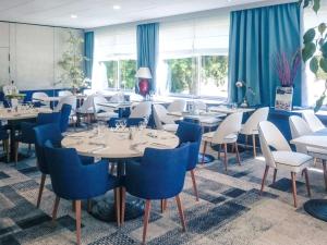马孔Hôtel Mercure Mâcon Bord de Saône的餐厅设有白色的桌子和蓝色的椅子