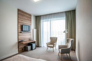 SochocinHotel Bonifacio SPA&SPORT Resort的酒店客房配有2把椅子、书桌和电视。