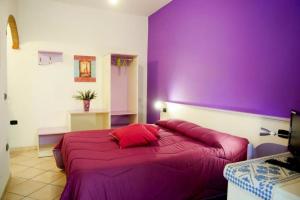 卡拉古诺内Affittacamere Casa del Sole的紫色卧室配有一张带红色枕头的大床