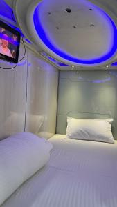 孟买Astropods的卧室配有白色床和天花板上的电视