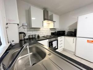 利物浦Wenlock Liverpool的厨房配有白色橱柜和不锈钢盥洗盆