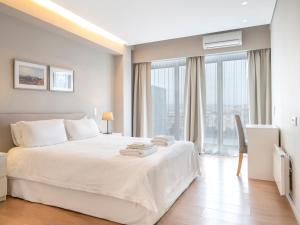 雅典雅典市中心阁楼公寓的卧室设有白色的床和大窗户