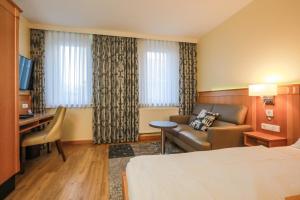 埃朗根加斯特豪斯克拉尔酒店的酒店客房配有一张床、一张沙发和一张书桌。