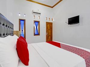 日惹Super OYO 92101 Elma Guesthouse的一间卧室配有两张带红色枕头的床和电视