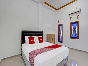 日惹Super OYO 92101 Elma Guesthouse的白色卧室配有一张带红色枕头的大床