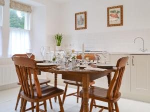Strachur花园度假屋的厨房配有木桌、带酒杯的椅子