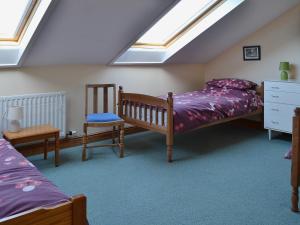 Soulby风海谷仓乡村别墅的阁楼卧室配有两张床和椅子