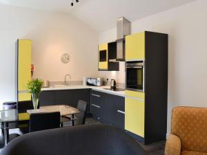 binbrookGranary Lodge的厨房配有黄色和黑色橱柜和桌子