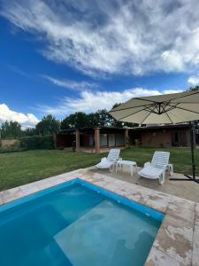 Vista FloresPergolas Guest House - Pileta, Vinos y Montaña的一个带两把椅子和一把遮阳伞的游泳池