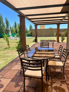 Vista FloresPergolas Guest House - Pileta, Vinos y Montaña的凉亭下带桌椅的天井