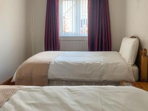 North SomercotesNursery Cottage的卧室内的两张床,配有紫色窗帘和窗户