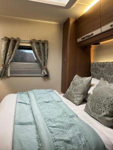 科舍姆Self Contained Holiday Home Caravan的一间卧室设有一张床和一个窗口