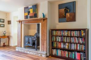 赛伦塞斯特Woodmancote Manor Cottage的客厅设有壁炉和书架。