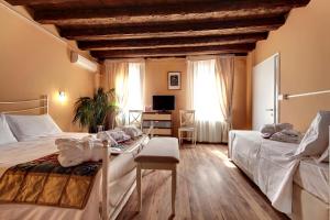 威尼斯卡里萨旅馆的一间卧室配有两张床和一张书桌及电视