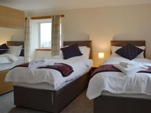 斯特兰拉尔Hawthorn Cottage的一间卧室设有两张床和窗户。
