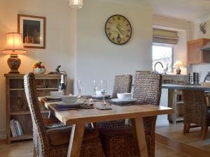HolmewoodLing Farm Cottage的餐桌、椅子和墙上的时钟
