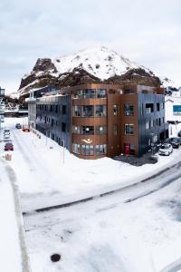 韦斯特曼纳埃亚尔Westman Islands Inn的公寓大楼的背景是一座白雪覆盖的山