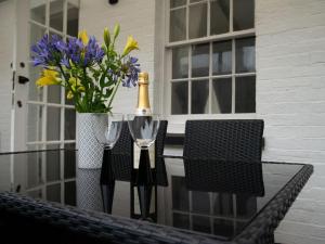 FelphamPebble Cottage的一瓶香槟和两杯鲜花桌子上的玻璃杯