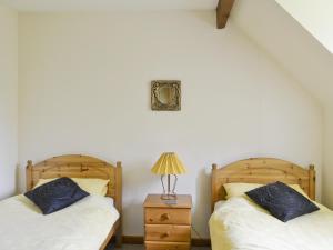 汤布里奇紫罗兰小屋的一间卧室配有两张床和一张带台灯的桌子